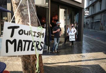 Restaurant workers look on after police used a water canon to disperse demonstrators protesting against coronavirus lockdown regulations in Cape Town, South Africa, July 24, 2020.