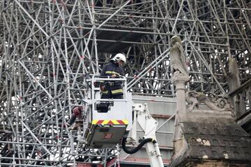  Un bombero trabaja en un elevador junto al andamiaje que cubre parte de la catedral de Notre Dame