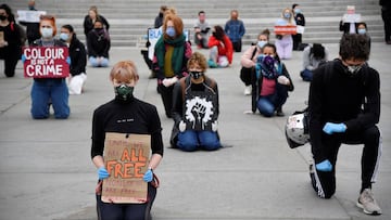 People wearing masks and holding signs kneel during a Black Lives Matter protest in Trafalgar Square in London, following the death of George Floyd who died in police custody in Minneapolis. London, Britain, June 5, 2020. REUTERS/Toby Melville