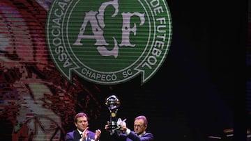 CONMEBOL&#039;s President Alejandro Dominguez (L) hands on the Copa Sudamericana trophy to the President of Brazil&#039;s Chapecoense Real club Plinio David during the Libertadores Cup draw in Luque, Paraguay, on December 21, 2016.