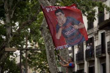An FC Barcelona supporter waves a flag with a picture of Luis Suarez, during celebrations for their team's victory in the Spanish league title at Canaletas source at Las Ramblas, in Barcelona, Spain, Saturday, May 14, 2016.