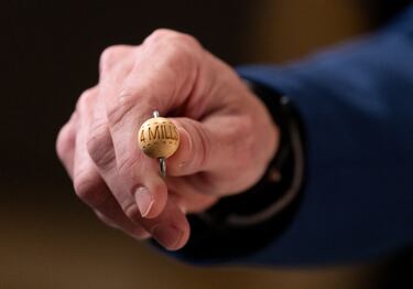 Un hombre enseña una bola con la cantidad de dinero de uno de los premios al inicio del Sorteo Extraordinario de la Lotería de Navidad.