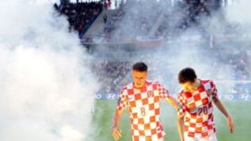 Ognjen Vukojevic (i) y Ivan Perisic intentan sacar del campo una bengala durante el comienzo del partido de la primera fase de la Eurocopa 2012, grupo C, ante Italia.