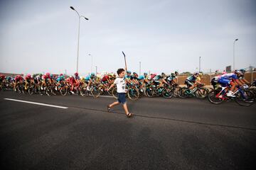 Un niño corre junto al pelotón.