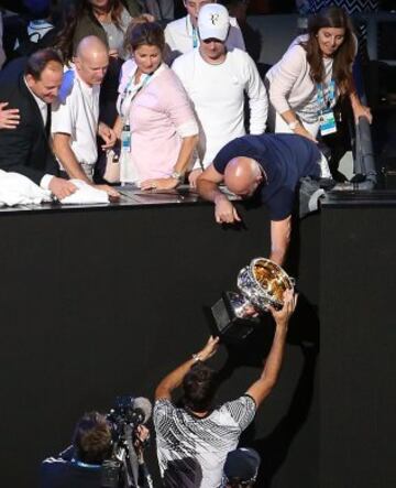 Roger Federer entrega el trofeo de ganador a un miembro de su equipo.