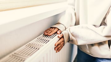 Woman warms up hands over heater