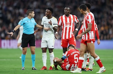 Almeria's Lucas Robertone reacts after sustaining an injury as Real Madrid's Vinicius Junior remonstrates to referee Francisco Maeso