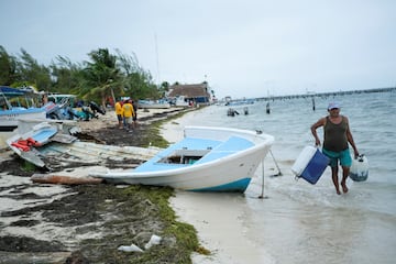 Un hombre lleva una hielera y un tanque de gasolina mientras la tormenta tropical Helene se acerca a la península de Yucatán, en Cancún.