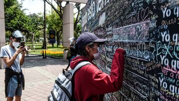 A woman writes on a giant blackboard what she wants to do when the new coronavirus pandemic is over, in Lima on October 26, 2020. - On giant blackboards placed in two squares in Lima, people can write with colored chalk what they want to do &quot;when this is over.&quot; (Photo by ERNESTO BENAVIDES / AFP)