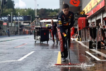 Un miembro del equipo Red Bull trata de achicar agua para evitar charcos que dañen los vehículos.