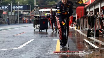 Un miembro del equipo Red Bull trata de achicar agua para evitar charcos que dañen los vehículos.