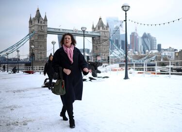 La gente camina por un recorrido que está cubierto de nieve cerca del Tower Bridge.