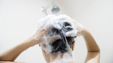 Lady using shampoo wash / clean her hair in a bathroom with splash shower spray water
