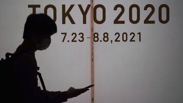 A man wearing a protective mask to help curb the spread of the coronavirus walks in front of he Tokyo 2020 Olympic Games advertisement Thursday, May 13, 2021, in Tokyo. The Japanese capital confirmed more than 1,000 new coronavirus cases on Thursday. (AP