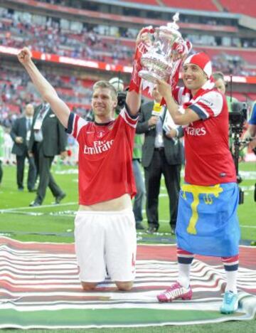 Per Mertesacker y Santi Cazorla jugadores del Arsenal levantan la Copa de Inglaterra, después de ganar la final de la Copa FA Inglesa contra el Hull City en el estadio de Wembley en Londres.