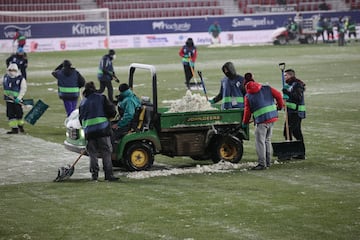 Operarios del club rojillo quitan la nieve del terreno de juego.