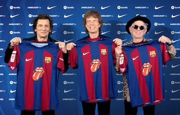 Members of the Rolling Stones, Ronnie Wood, Mick Jagger and Keith Richards pose for a picture as they hold FC Barcelona jerseys with the iconic tongue in the center of them,