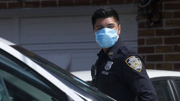 An NYPD officer helps remove a patient from a house in Queens.