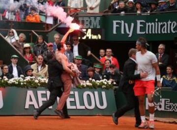 Un manifestante corre a la cancha con una bengala encendida durante el partido de la final individual masculina entre Rafael Nadal y David Ferrer en Roland Garros