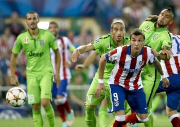 El delantero croata del Atlético de Madrid Mario Mandzukic (2d) persigue el balón junto al uruguayo Martín Cáceres (3d) y el chileno Arturo Vidal (d), de la Juventus, durante el partido de la segunda jornada de la fase de grupos de la Liga de Campeones que se disputa esta noche en el estadio Vicente Calderón, en Madrid. 