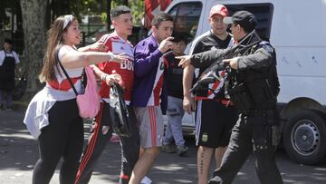 A police officer points at fans of River Plate's soccer team outside Antonio Vespucio Liberti stadium after the final Copa Libertadores match against rival Boca Juniors was suspended for a second day in a row in Buenos Aires, Argentina, Sunday, Nov. 25, 2018. In one of the most embarrassing weekends in South American football history, the Copa Libertadores final was once more postponed on Sunday. The same decision was made on Saturday after Boca's bus was attacked by River fans. (AP Photo/Diego Martinez)