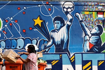 FILE PHOTO: A resident stands near a mural depicting the famous "Hand of God" goal by former Argentine soccer star Diego Maradona, in light of the upcoming 2010 FIFA World Cup at the Agua Santa neighborhood in Rio de Janeiro May 21, 2010. 