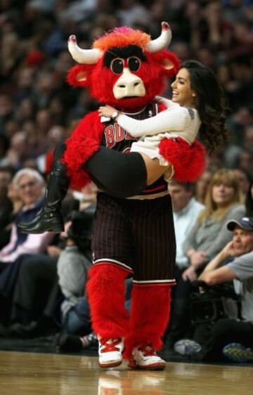 Benny, la mascota de los Chicago Bulls, lleva en brazos a una aficionada.