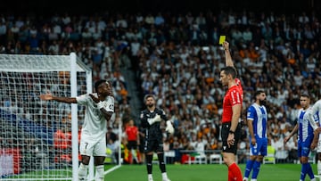El colegiado Alejandro Muñiz Ruiz muestra tarjeta amarilla al delantero del Real Madrid Vinícius.