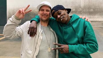 Las leyendas del skate Chad Muska y Kareem Campbell, ambos con gorra y sonriendo, haciendo el se&ntilde;al de la victoria con los dedos. 