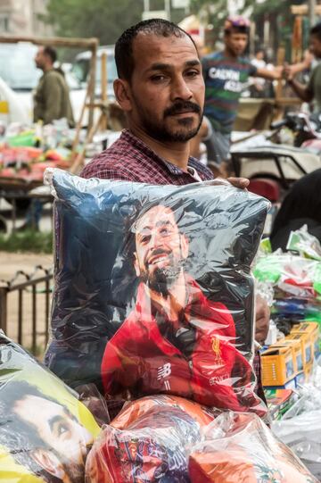 Un vendedor egipcio posa con una almohada de su mercancía en la que se puede ver al delantero egipcio del Liverpool Mohamed Salah en una calle de la capital, El Cairo.