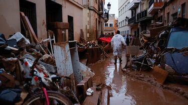 A person walks past residents' belongings covered in mud, following heavy rains that caused floods, in Paiporta, near Valencia, Spain, November 4, 2024. REUTERS/Eva Manez