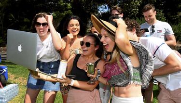 Un grupo de apostadores sigue la carrera de caballos de la Copa de Melbourne, a través de un ordenador portátil y de un teléfono móvil, en un parque junto al hipódromo de Flemington (Melbourne), con pícnic incluido. Debido a la pandemia, las carreras se celebran a puerta cerrada y los espectadores recurren a la tecnología para no perderse detalle.