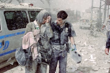 El oficial de polic¨ªa Mike Brennan ayuda a una mujer angustiada conocida solo como Beverly, mientras cenizas y escombros cubren el ¨¢rea luego del colapso del 1 World Trade Center (torre norte).