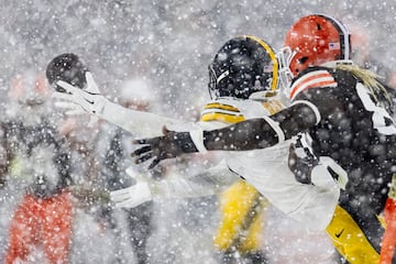 Beanie Bishop Jr. de los Pittsburgh Steelers, y David Njoku Cleveland Browns. Tratan de agarrar el balón bajo la nieve.