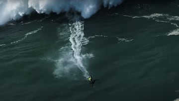 El surfista portugu&eacute;s Nic Von Rupp, vestido con un neopreno integral negro, cayendo de su tabla de sur amarilla en el bottom de una ola gigante en Praia do Norte, Nazar&eacute; (Portugal), este invierno 2021. 