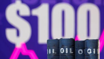 Models of oil barrels are seen in front of a displayed rising stock graph and "$100" in this illustration, February 24, 2022.
