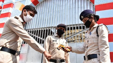 A security personnel (R) of Netaji Subhash Chandra Bose central jail checks the temperature of duty policemen during a government-imposed nationwide lockdown as a preventive measure against the COVID-19 coronavirus in at Netaji Subhash Chandra Bose centra