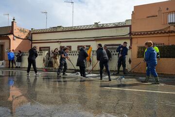 Varios vecinos de la calle Buen Pastor, de San Fernando, barren el agua a la alcantarilla, a 31 de octubre de 2024, en Cádiz.