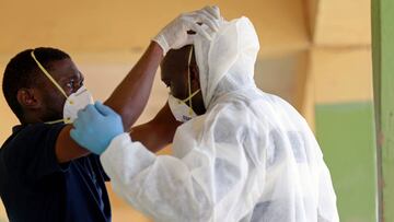 A medical health worker helps his colleague to put on his PPE during a community testing in Abuja. 