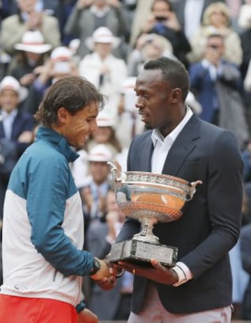 Rafael Nadal recibe el trofeo de manos del velocista jamaiquino Usain Bolt después de derrotar a su compatriota David Ferrer en la final de Roland Garros