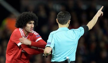 Fellaini protests to referee Milorad Mazic (right) after being booked at Old Trafford on Thursday night.