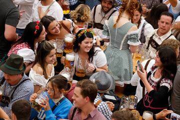 Visitors pose for pictures while holding mugs of beer during the official opening the world's largest beer festival, the 187th Oktoberfest in Munich, Germany, September 17, 2022. REUTERS/Michaela Rehle