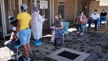 A healthcare worker speaks with a woman queuing for a PCR Covid-19 test at the Lancet laboratory in Johannesburg on November 30, 2021. - A new, heavily mutated Covid-19 variant, dubbed omicron, spread across the globe on Sunday, shutting borders and renew