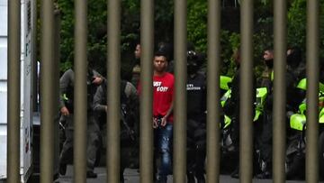 Police officers escort one of the suspects in the execution-style killing of a Paraguayan anti-drug prosecutor during his honeymoon, at the public prosecutor's office, to take him to the airport in Medellin, Colombia, on June 3, 2022. - Police in Colombia have arrested all the suspects in the killing of Paraguayan anti-drug prosecutor Marcelo Pecci, Colombian President Ivan Duque said Friday. Pecci was felled by two shots while he was on a beach with his new wife on the Colombian resort island of Baru on May 10. (Photo by Joaquin SARMIENTO / AFP) (Photo by JOAQUIN SARMIENTO/AFP via Getty Images)