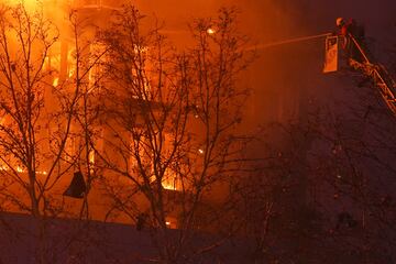 Un incendio de grandes dimensiones arrasa un edificio de 14 plantas generando una gran columna  de fuego y una densa humareda dificultano a los bomberos las labores de extición. En la imagen, un bombero trabaja durante el siniestro.