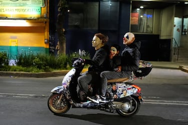 Personas con máscaras recorren las calles en motocicleta durante un desfile de Halloween en la Ciudad de México.