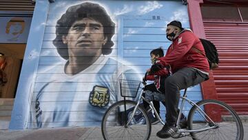A man rides a bicycle past a mural painted by artist Marley outside the Diego Armando Maradona stadium as people are gathering to commemorate the Argentine legend's second goal against England during the FIFA World Cup Mexico 1986 on its 35th anniver