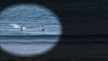 Un tiburón cazando una tortuga detrás de dos surfistas en Ala Moana, Honolulu, Hawái, el viernes 28 de mayo del 2023.