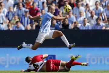 El delantero neerlandés-marroquí del Málaga, Nordin Amrabat (arriba), autor del cuarto gol de penalti, salta ante el defensa del Rayo Vallecano Antonio Amaya, durante el encuentro de la novena jornada de Liga en Primera División que Málaga y Rayo Vallecano están disputando en el estadio de La Rosaleda, en Málaga.