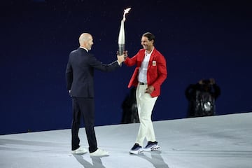 El exfutbolista del Real Madrid y de la selección francesa, ZInedine Zidane, entrega la antorcha olímpica al tenista, Rafa Nadal, durante la ceremonia de apertura de los Juegos Olímpicos de París 2024.